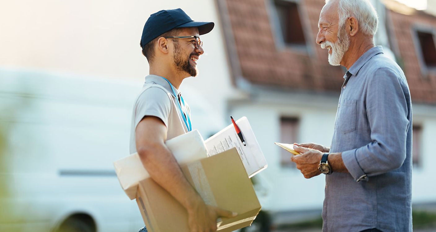 Postbote gibt Paket an älteren Herren.