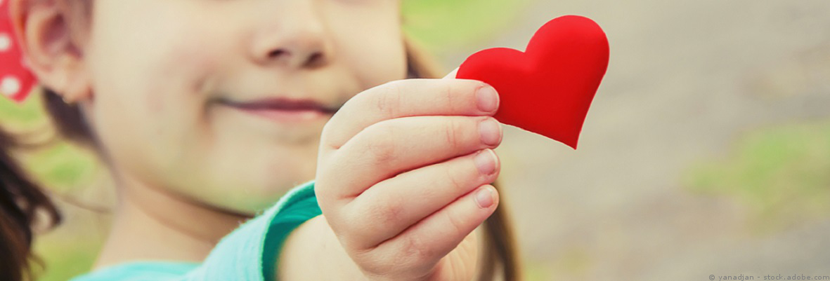 Kind hält ein Papierherz in der Hand